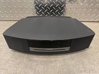 Front view of Bose Wave music system showing speaker grills and CD slot with Bose logo.