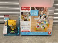 Photo of the yellow lion toy in packaging and Fisher Price Zebra Walker box showing product image and branding