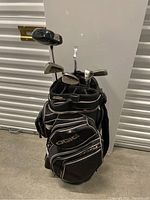 Full view of the golf bag loaded with multiple clubs including driver and irons, standing on concrete floor
