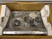 Top view of the kitchen vent hood inside packaging showing stainless steel body, dual fan filters, and ducting parts.