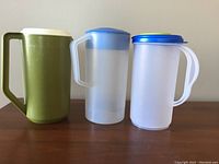 Three plastic juice jugs: green Rubbermaid, frosted Rubbermaid with blue lid, frosted Sterilite with blue-green lid