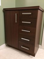 Front view of the cabinet showing five drawers with silver handles on the right, and a single door with vertical handle on the left side.