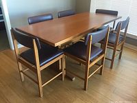 Six chairs arranged around rectangular wood table in room