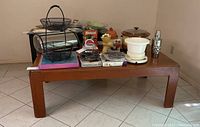Full view of the rectangular wooden coffee table with various items placed on top, showing the teak veneer finish and solid legs.