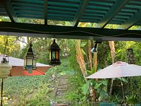 Four outdoor hanging lanterns suspended under a patio cover, showing their varying styles and colors.