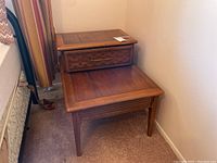 Full view from the side showing both tiers of the wooden side table next to a bed.
