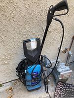 Front angle view of the Campbell Hausfeld pressure washer showing the handle, hose, and power cord wrapped around the unit.