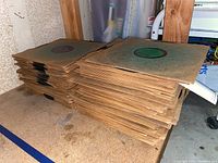 Stacks of vintage 78 RPM vinyl records in aged paper sleeves with visible labels, stacked horizontally on a shelf.