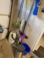 Full view showing all cleaning tools, vacuum, bucket, and the trashcan grouped in corner of the room.
