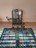Metallic wine racks and rug arranged on floor against wall, showing full items.