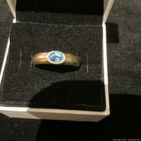 Top view of ring in white presentation box on black felt showing overall appearance and setting