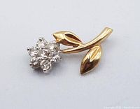 Front view of pendant showing diamond-set white gold flower head and yellow gold stem with leaves.