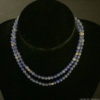 Full view of the necklace displayed doubled on a black bust showing its length and bead layout.