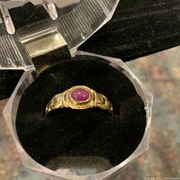 Ring displayed in clear plastic box on black felt to show general appearance and color
