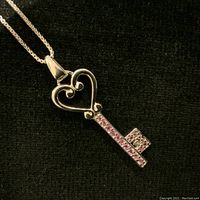Close-up of EFFY sterling silver key pendant showing pink gemstones and heart-shaped top against black background.