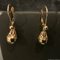 Two gold dangle drop earrings front view on black background