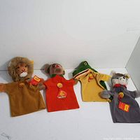 Front view of four Steiff hand puppets arranged side by side showing lion, mouse, crocodile and cat