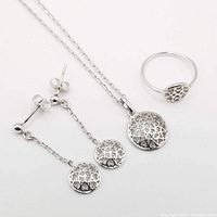 Sterling silver jewelry suite with pendant, chain, earrings and ring displayed on white background.