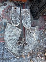 Five weathered antique cast iron architectural pieces arranged on ground with visible decorative motifs and weathered surface