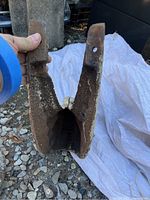 Photo showing U shaped cast iron roof corner piece held upright, resting on gravel ground