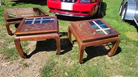 Pair of Asian style wooden side tables shown outdoors on grass next to vehicles, illustrating overall appearance, style, and scale.