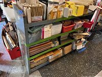 Front view of the metal shelving unit loaded with various boxes and containers, showing the shelf construction and wear.