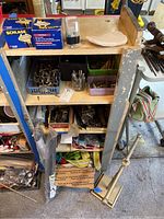 Shelf with multiple hardware items including vintage hooks, door knob boxes, and assorted small metal parts.
