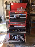 Overall view of a red Craftsman metal toolbox with several drawers, some open showing tools inside.