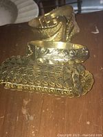 Three vintage gold-tone fashion bracelets stacked together showing different textures and details