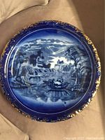 Full view of the antique flow blue ironstone plate showing the central scenic pattern and gold-trimmed ornate rim.