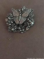 Front view of the pewter butterfly and floral pin showing intricate details.