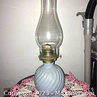 Full view of the blue glass oil lamp with clear glass chimney, showing the wick and brass burner