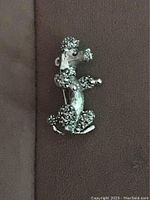 Front view of vintage poodle brooch showing silver-tone metal with detailed curly texture on fur and sitting poodle profile.