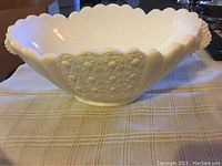 Top view of oval milk glass bowl showing scalloped edge, Daisy and Button textured panels, and molded handles.