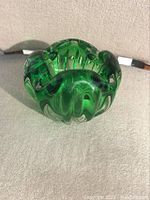 Front angled view of green glass bowl showing ribbed design and petal-like edge.