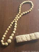 Photo showing full view of the carved necklace with round carved beads and the rectangular carved bracelet.