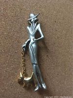 Front view of the pewter brooch showing the lady and her dog leash chain with the dog at her feet.