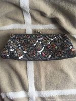 Full view of vintage Rachel beaded and sequined clutch handbag with scallop patterned bead and sequin embellishments on light fabric background.
