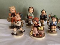 Front view of the six Hummel Goebel figurines arranged side by side showing colors, poses, and details
