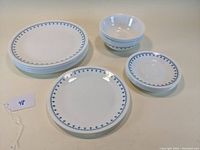 Full set of plates, bowls, and saucers laid out on a table showing the pattern and quantity.