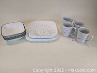 Top view of 6 bowls on the left, 5 dinner plates center, and 4 mugs on the right showing the gray swirl pattern on white Corelle dinnerware.