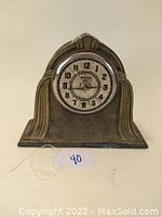 Frontal image of the Art Deco brass mantel clock showing dial and clock face details.