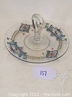 Round clear glass center handled serving plate with colorful Art Deco style decoration around the rim.