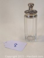 Full view of the tall clear glass talcum jar with silver floral embossed lid and finial seen from front. Tag '8' visible beside the jar.