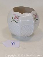 White Belleek porcelain vase with pink floral designs and embossed basket weave, scalloped rim, shown from angled front