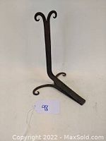 Front view image of metal doorstop with curled ends shaped like rams horns and angled spring bottom, plain background