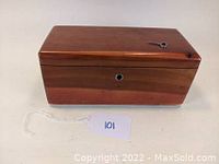 Front view of cedar chest closed, showing wood grain and keyhole.