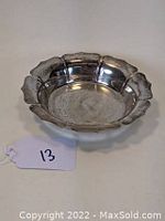 View of the sterling silver bowl from a near-angle showing scalloped edge and polished interior surface with some light wear marks.
