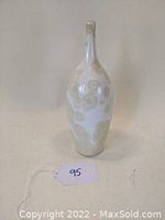 Front view of the mid century style narrow neck bottle form vase with beige and white circular patterning on ceramic surface.