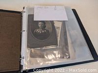 Black 3-ring binder open to show plastic sleeves containing vintage black-and-white portrait photographs and paper ephemera.